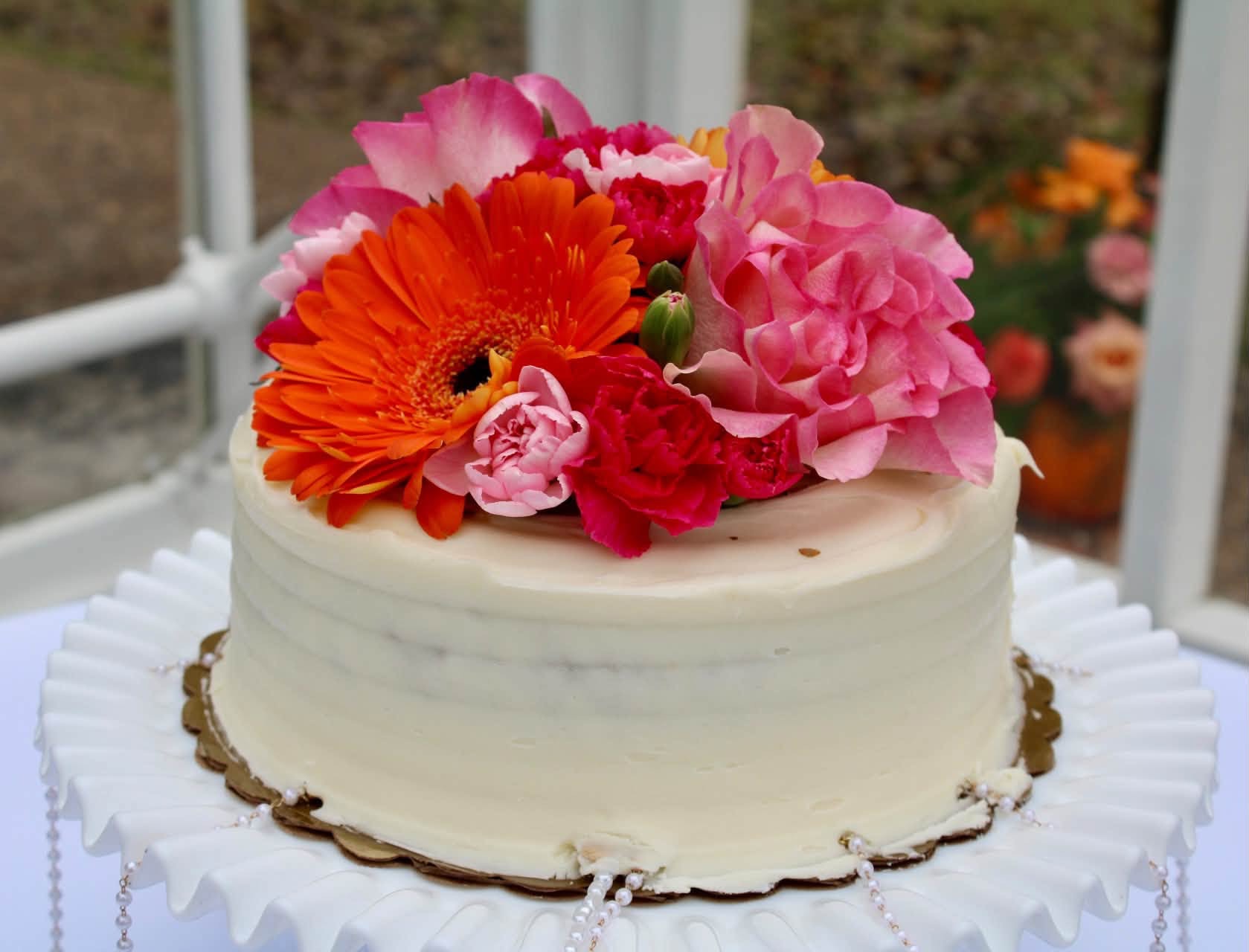 Fresh pink and orange flowers decorating a cake